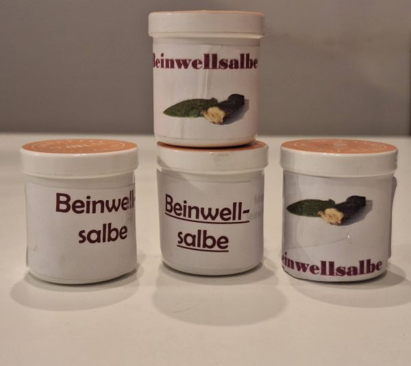 Verschiedene Becher mit Beinwell-Salbe auf einem Tisch. Natural Produkte aus Zell am See.