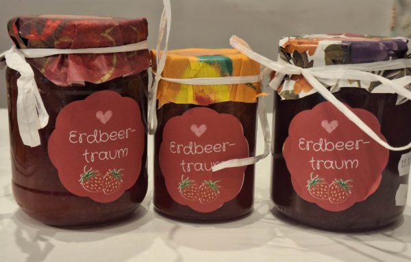 Drei Gläser mit Erdbeermarmelade, liebevoll dekoriert und beschriftet.