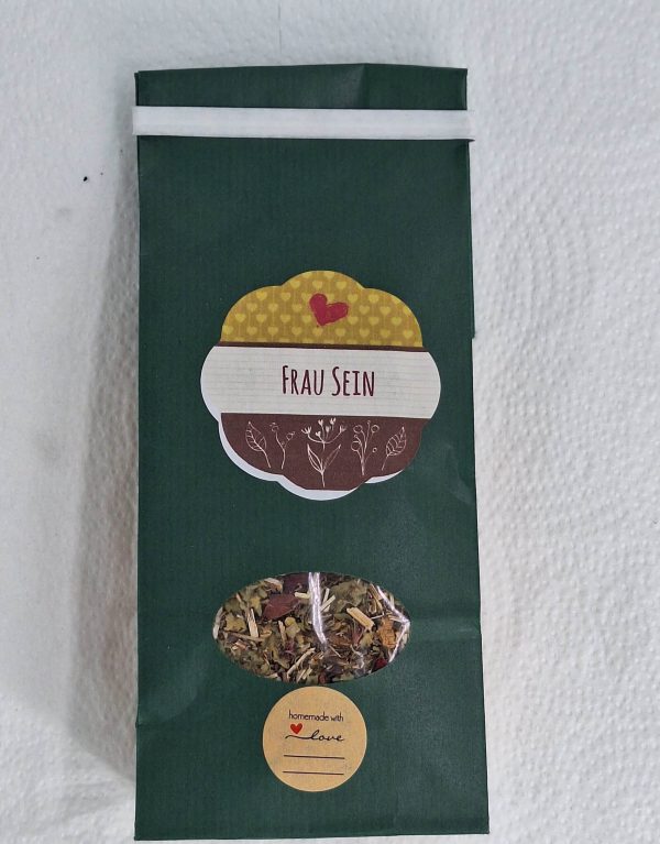 Kräutertee "Frau Sein" in grüner Verpackung, liebevoll handgemacht mit einem herzlichen Etikett.