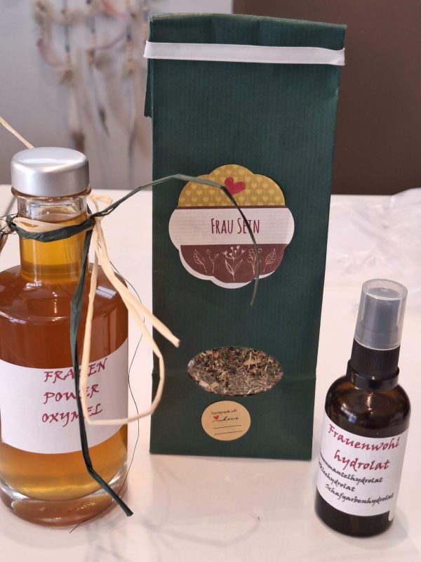 Handgemachte Naturprodukte: Oxymel, Kräuter und Hydrolat in stilvoller Präsentation.