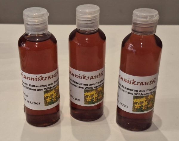 Drei Flaschen Johanniskrautöl aus frischem Wildkraut auf einem weißen Hintergrund.