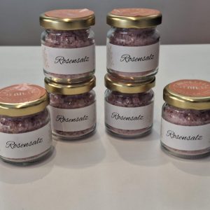 Sechs Gläser mit Rosensalz auf einem Tisch, ein schönes Geschenk für Naturprodukte.