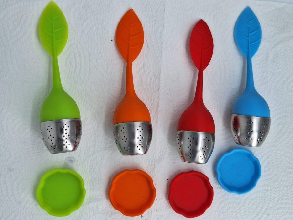 Bunte Teefilter in Blattform mit passenden Untersetzern, ideal für Teeliebhaber.