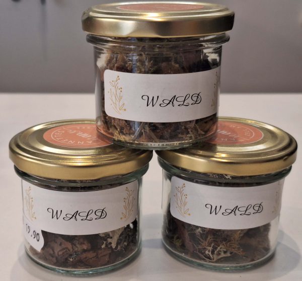 Drei Gläser mit Waldkräutern, beschriftet und in einem ansprechenden Design präsentiert.