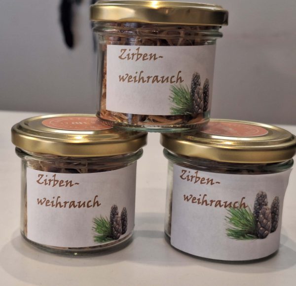 Drei Gläser mit Zirben-Weihrauch, dekoriert mit Etiketten und goldenen Deckeln.