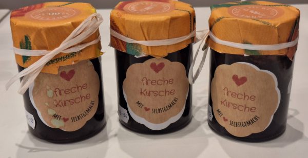 Drei Gläser mit dem Etikett "freche Kirsche" und buntem Deckel, handgemacht aus Zell am See.