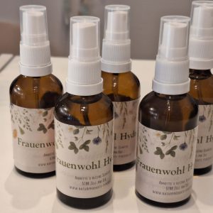 Fünf Flaschen Frauenwohl Hydrolat mit floralem Etikett auf einem Tisch.