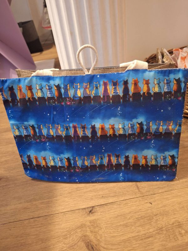 Tasche mit bunten Katzenmotiven auf blauem Hintergrund, ideal als kreative Geschenkidee.