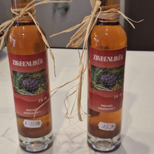 Zwei Flaschen Zirbenlikör mit Preisen und dekorativen Bändern auf einem Tisch.